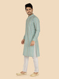 Man wearing a green and white patterned kurta with white pants