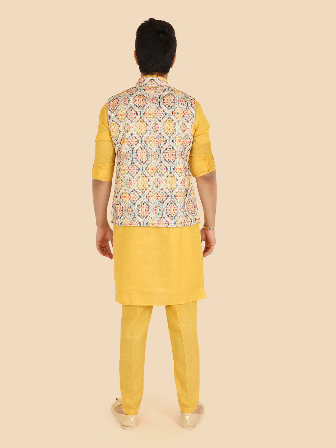 Person wearing a gold kurta with a patterned vest 